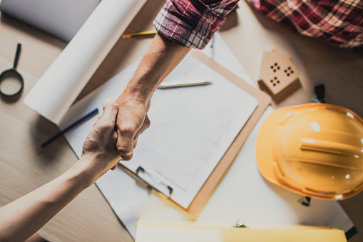 top view hand shake of engineer and building contractor on table top view hand shake of engineer and building contractor on table